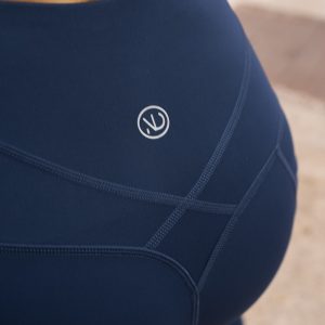 Woman wearing a compression legging. This sleek flattering legging is completely Squat proof, with an Ultra High Waistband with an adjustable flatline drawstring elastic.
