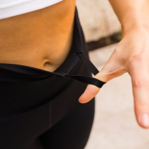 Woman wearing a compression legging. This sleek flattering legging is completely Squat proof, with an Ultra High Waistband with an adjustable flatline drawstring elastic.