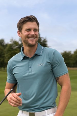 A golfer wearing a golf polo that was designed in a performance-stretch material with moisture managing properties for all day comfort.