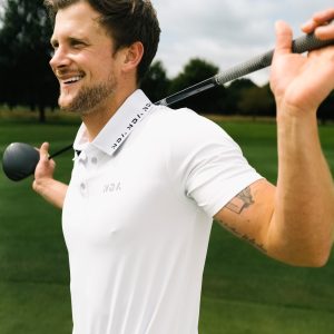 A golfer wearing a golf polo that was designed in a performance-stretch material with moisture managing properties for all day comfort.