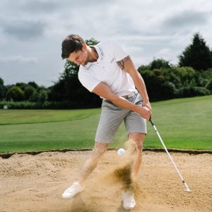 A golfer wearing a golf polo that was designed in a performance-stretch material with moisture managing properties for all day comfort.