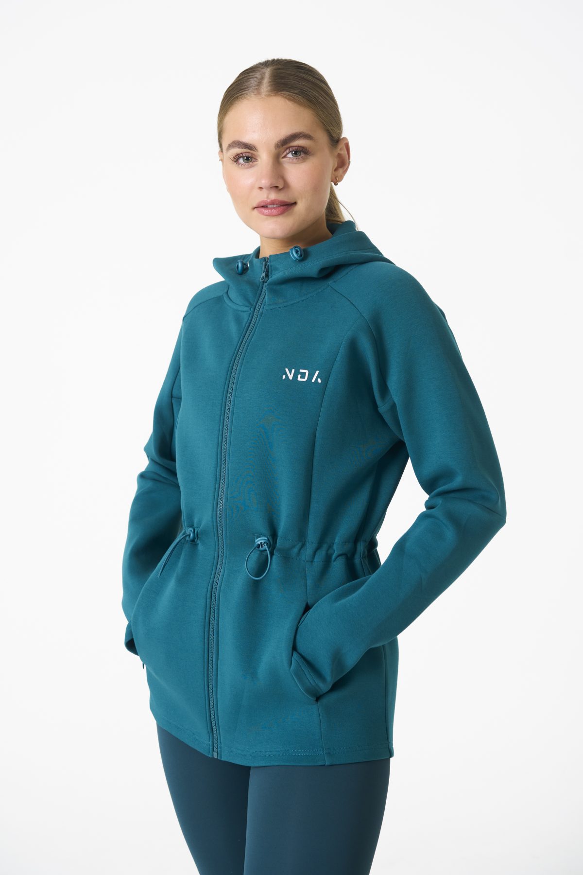 Elevate your activewear game with the Legacy Zip Hoodie (Dark Teal) from our Legacy Activewear Collection. Designed for ultimate movement, support, and comfort, this hoodie seamlessly blends practicality with style. The full-zip closure offers effortless wearability, while the adjustable hood and elasticated waist ensure a personalized fit. Perfect for your on-the-go lifestyle, it features two convenient pockets: a secure zipped pocket for essentials and a classic open pocket for quick access. The Legacy Zip Hoodie is your go-to for both functionality and trend-forward fashion.