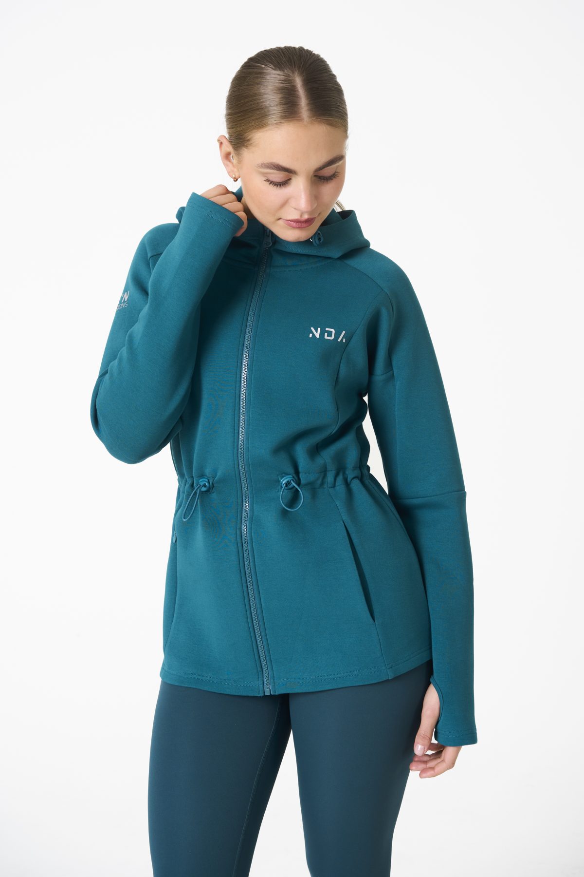 Elevate your activewear game with the Legacy Zip Hoodie (Dark Teal) from our Legacy Activewear Collection. Designed for ultimate movement, support, and comfort, this hoodie seamlessly blends practicality with style. The full-zip closure offers effortless wearability, while the adjustable hood and elasticated waist ensure a personalized fit. Perfect for your on-the-go lifestyle, it features two convenient pockets: a secure zipped pocket for essentials and a classic open pocket for quick access. The Legacy Zip Hoodie is your go-to for both functionality and trend-forward fashion.