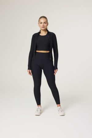 The Signature Rib Zip Jacket (Black) is the perfect fusion of structure and softness — designed to enhance your shape while keeping comfort at the forefront. Crafted from premium ribbed fabric with just the right amount of stretch, this jacket contours effortlessly to your body. The full-zip front offers versatile styling, while the seamless collar keeps the look sleek and streamlined. A subtle logo detail on the side adds a premium, understated touch. Whether you're heading to the studio or layering up post-workout, this jacket moves with you and flatters every angle.