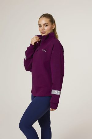 Premium & Practical - the Deluxe ¼ Zip (Mulberry). Made from our deluxe material, this 1/4 zip is designed to keep you warm and cosy during the colder months. The fabric is soft & heavy to the touch and provides ultimate comfort, making it a must-have for your wardrobe. Featuring a 1/4 zip and two pop up buttons on each side, this 1/4 zip not only offers functionality but also adds a touch of style to your look. The zipper allows for easy wear and the buttons add a unique element to the design.