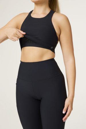 Sleek, supportive, and effortlessly flattering — the Signature Rib 2-in-1 Top (Black)  is your new go-to for active days and beyond. Designed in our signature ribbed fabric, this top features a built-in under bra for light-to-medium support, creating a streamlined 2-in-1 silhouette that sculpts and moves with you. The high neckline and removable padding offer coverage and flexibility, while the seamless construction keeps you comfortable through every workout. Finished with a subtle logo detail for a refined look, this piece pairs perfectly with our Ribbed Compression Legging and Signature Rib Zip Jacket.